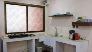 A compact kitchen with a window, a sink, and a countertop with various appliances. - Oasis studio - Great location (Vientiane)