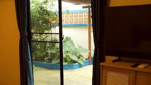 A room with a large window, a television on a wooden stand, and a blue curtain. - Oasis studio - Great location (Vientiane)