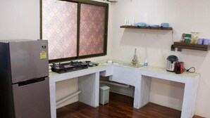 A compact kitchen with a refrigerator, stove, sink, and a window with patterned curtains. - Oasis studio - Great location (Vientiane)