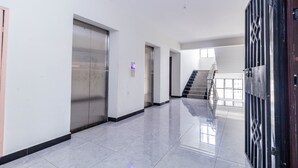 Ein geräumiger, moderner Korridor mit poliertem Boden, großen Metalttüren und einer Treppe, die in einen oberen Bereich führt.