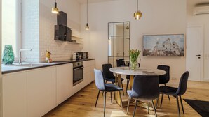 Una cucina moderna con mobili bianchi, un'isola centrale e illuminazione a sospensione.