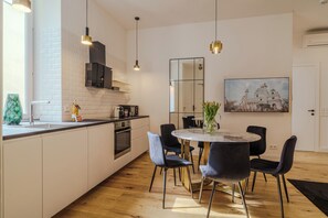 A modern kitchen with white cabinetry, a central island, and pendant lighting. - Grand Quarters Mariahilf Residence (Vienna)