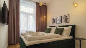 Un letto rifatto con lenzuola bianche, una testiera verde e un comodino.