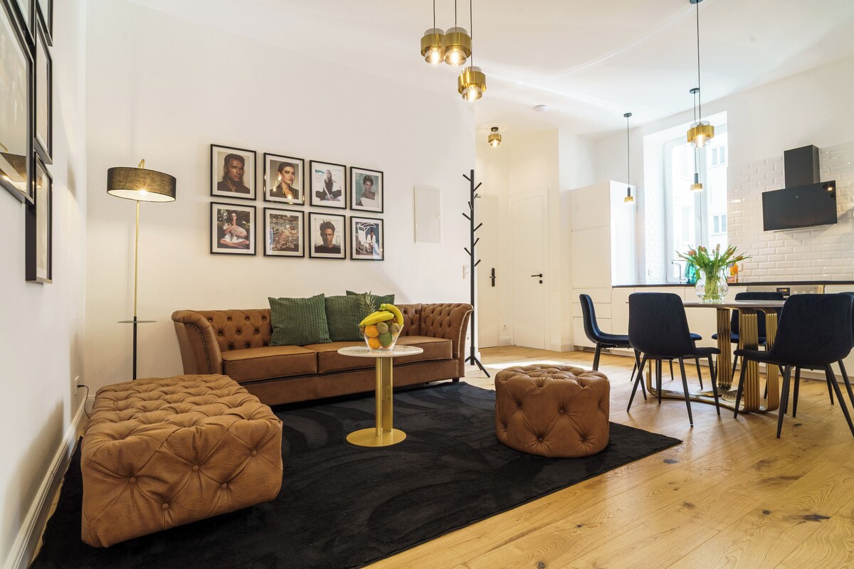 A modern living room with a sofa, ottoman, and dining area with chairs and a table.