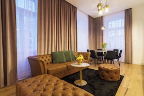 A modern living room with a brown sofa, a round coffee table, and a tufted ottoman. - Grand Quarters Mariahilf Residence (Vienna)