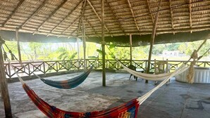A covered outdoor area with a concrete floor, wooden beams, and a thatched roof. There are two hammocks hanging from the beams. - Villa Tropical Studio No. 9, near the beach, Cabarete (Cabarete)