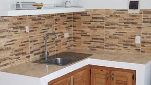 A modern kitchen with a built-in sink, wooden cabinets, and a backsplash with a wood-like pattern. - Villa Tropical Studio No. 9, near the beach, Cabarete (Cabarete)