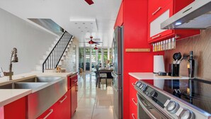 A modern kitchen with red cabinetry, stainless steel appliances, and a central island. - Relaxing Beach Villa in Dorado (Dorado)