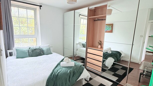 Une chambre à coucher moderne avec un grand lit, une commode, un miroir et une table en verre.