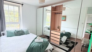Une chambre moderne avec un grand lit, une commode, un miroir et une table en verre.