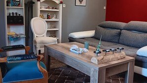 Ett vardagsrum med en soffa, ett soffbord, en fåtölj, en bokhylla och en röd accentvägg.