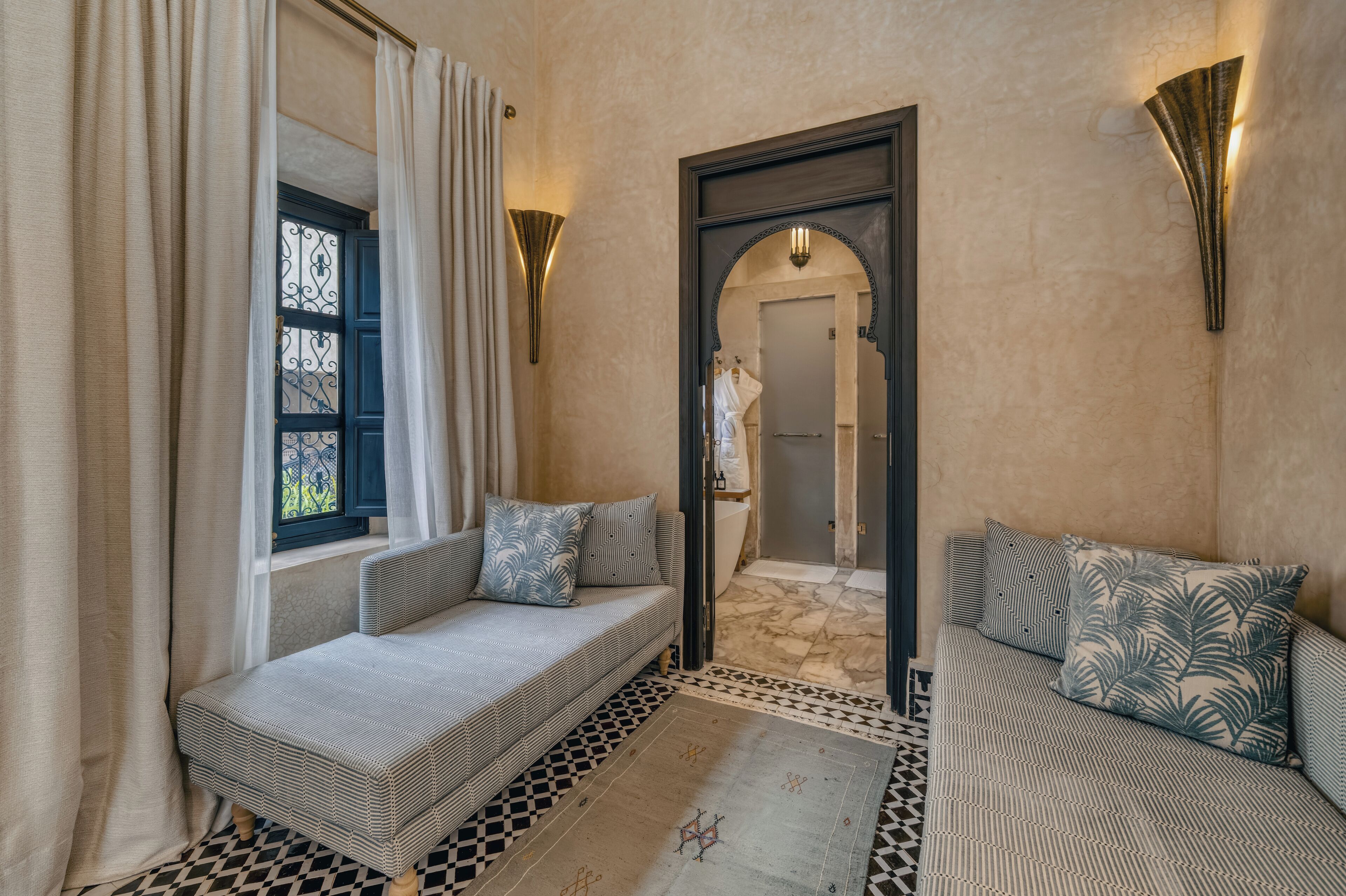 A room with a sofa, a patterned rug, and a window with curtains.