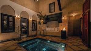 A luxurious room with a large tiled pool, arched doorways, and elegant wall sconces. - Riad Dar Yuba  (Marrakech)