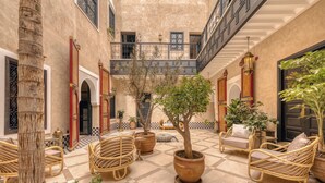 A courtyard with wicker furniture, potted plants, and a checkered floor. - Riad Dar Yuba  (Marrakech)