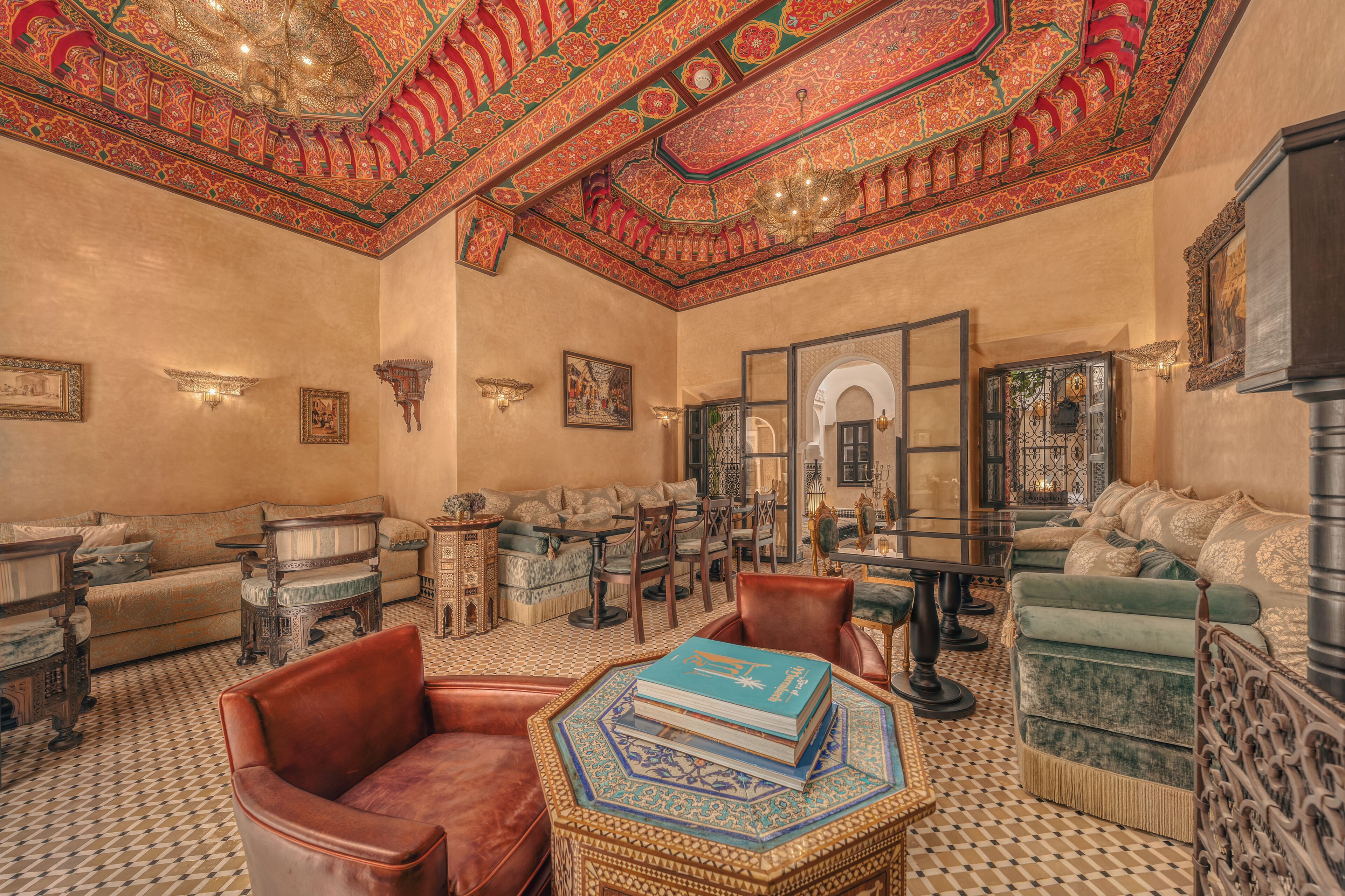 A richly decorated room with ornate ceiling patterns, a variety of seating options including sofas and chairs, and a patterned floor.