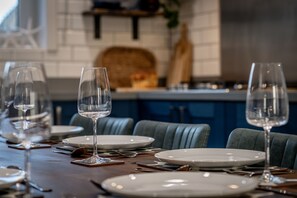 Mesa posta com pratos brancos, copos de vinho transparentes e talheres.
