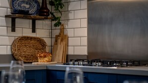 Una cucina con un fornello, un cesto di vimini e un tagliere di legno.
