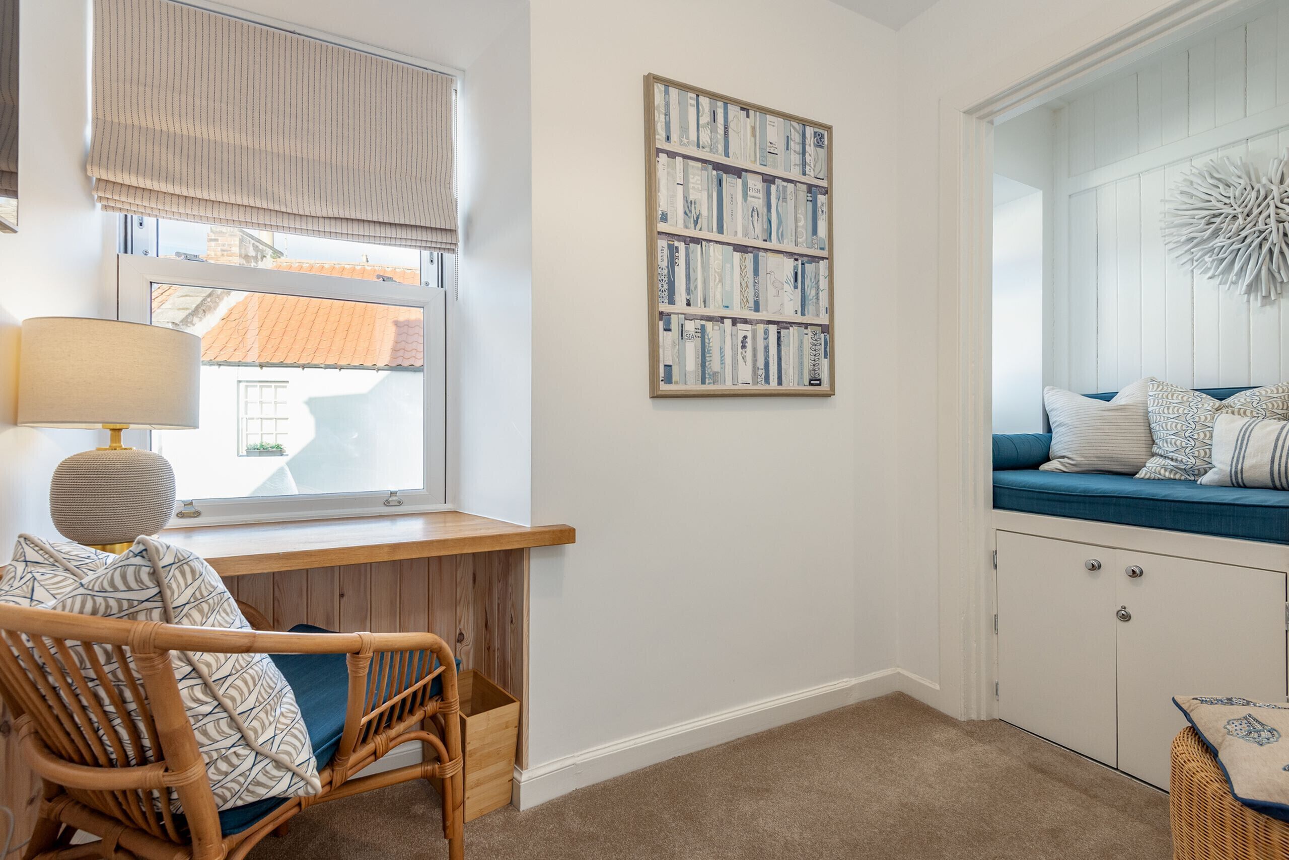 A cozy room with a wicker chair, a bookshelf, and a built-in bench with cushions.