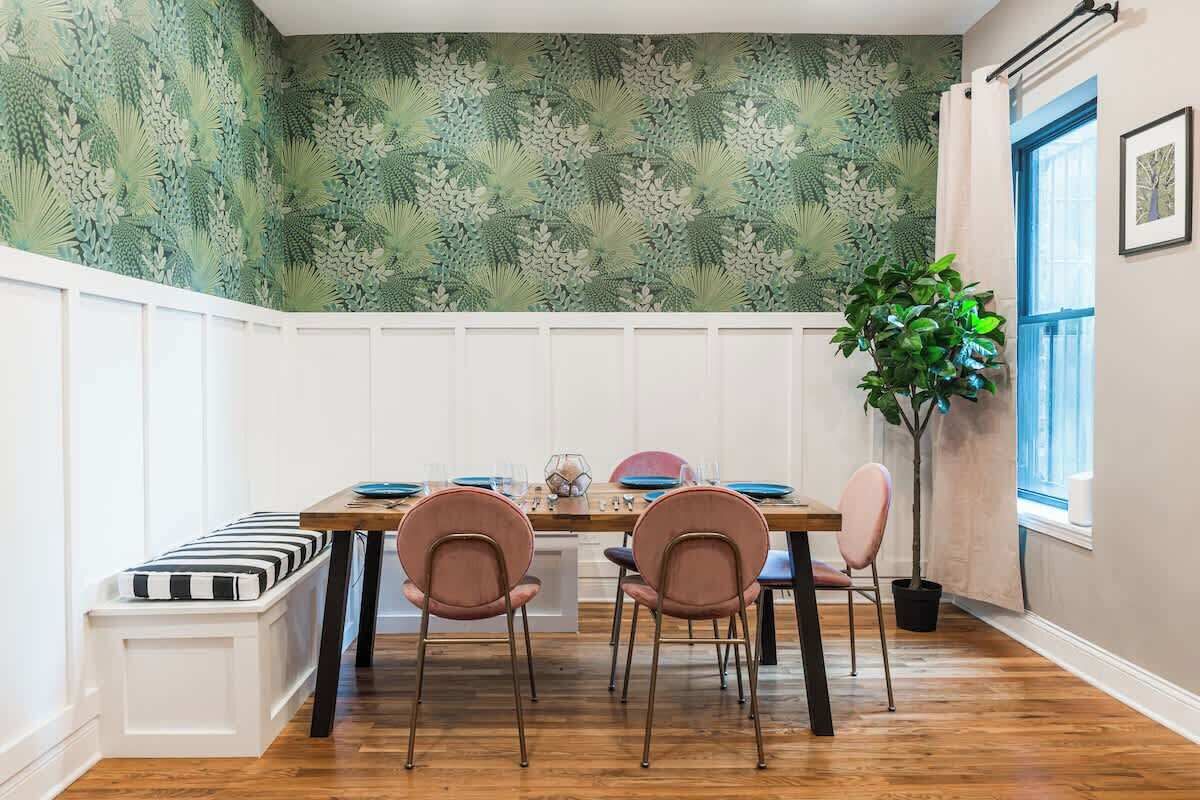 A dining area with a wooden table, four chairs, a bench, and a potted plant.