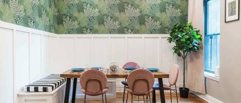 A dining area with a wooden table, four chairs, a bench, and a potted plant.