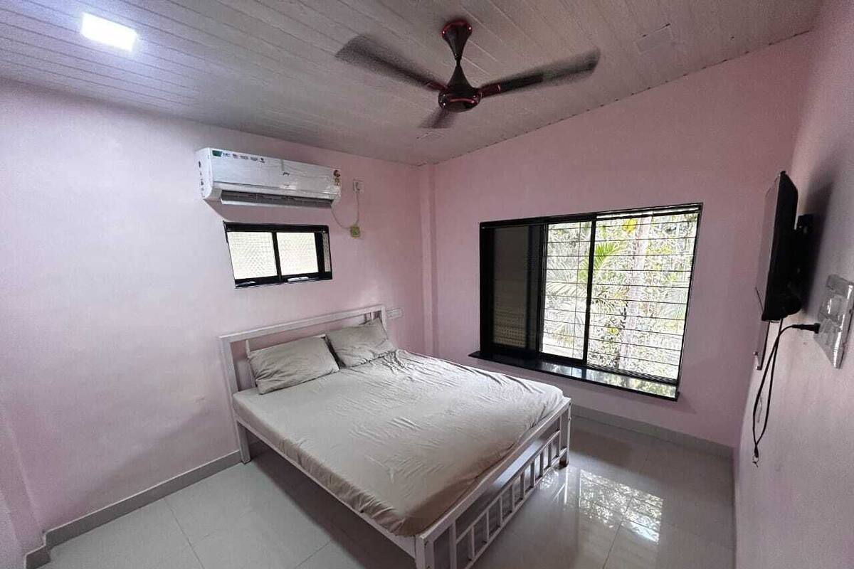 Une chambre à coucher comprenant un lit, un climatiseur, une fenêtre avec des stores et un ventilateur de plafond.