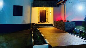 Una casa moderna con un ingresso ben illuminato, un vialetto in pietra e un piccolo giardino.