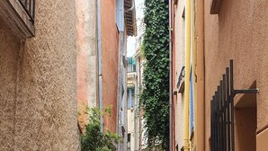 Eine enge Kopfsteinpflasterstraße, begrenzt von Gebäuden mit Balkonen und einem verschlossenen Eingang.