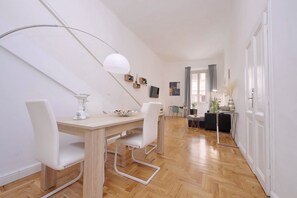 A modern dining area with a wooden table, white chairs, and a pendant light. - TRASTEVERE CAMPO de FIORI ROME by FOOT-NETFLIX-AIRCOND-WIFI (Roma)