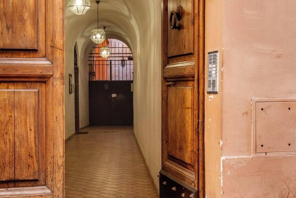 A hallway with wooden doors and a tiled floor, leading to a dark door at the end.