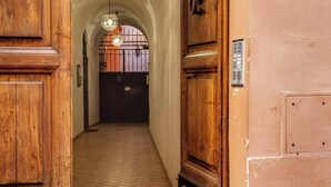 A hallway with wooden doors and a tiled floor, leading to a dark door at the end. - TRASTEVERE CAMPO de FIORI ROME by FOOT-NETFLIX-AIRCOND-WIFI (Roma)