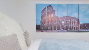 A bedroom with a large bed, a white fluffy pillow, and a wall-mounted picture of the Colosseum. - TRASTEVERE CAMPO de FIORI ROME by FOOT-NETFLIX-AIRCOND-WIFI (Roma)