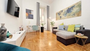 A modern living room with a sofa, a coffee table, and a TV mounted on the wall. There are two potted plants and a world map artwork on the wall. - TRASTEVERE CAMPO de FIORI ROME by FOOT-NETFLIX-AIRCOND-WIFI (Roma)