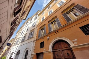 A narrow street with buildings featuring arched windows and a large wooden door. - TRASTEVERE CAMPO de FIORI ROME by FOOT-NETFLIX-AIRCOND-WIFI (Roma)