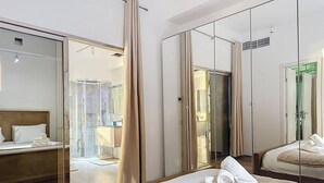A hotel room with a large mirror, a bed with white linens, and a view into the bathroom. - Stunning 2 bed in Sadaf 6 (Dubai)