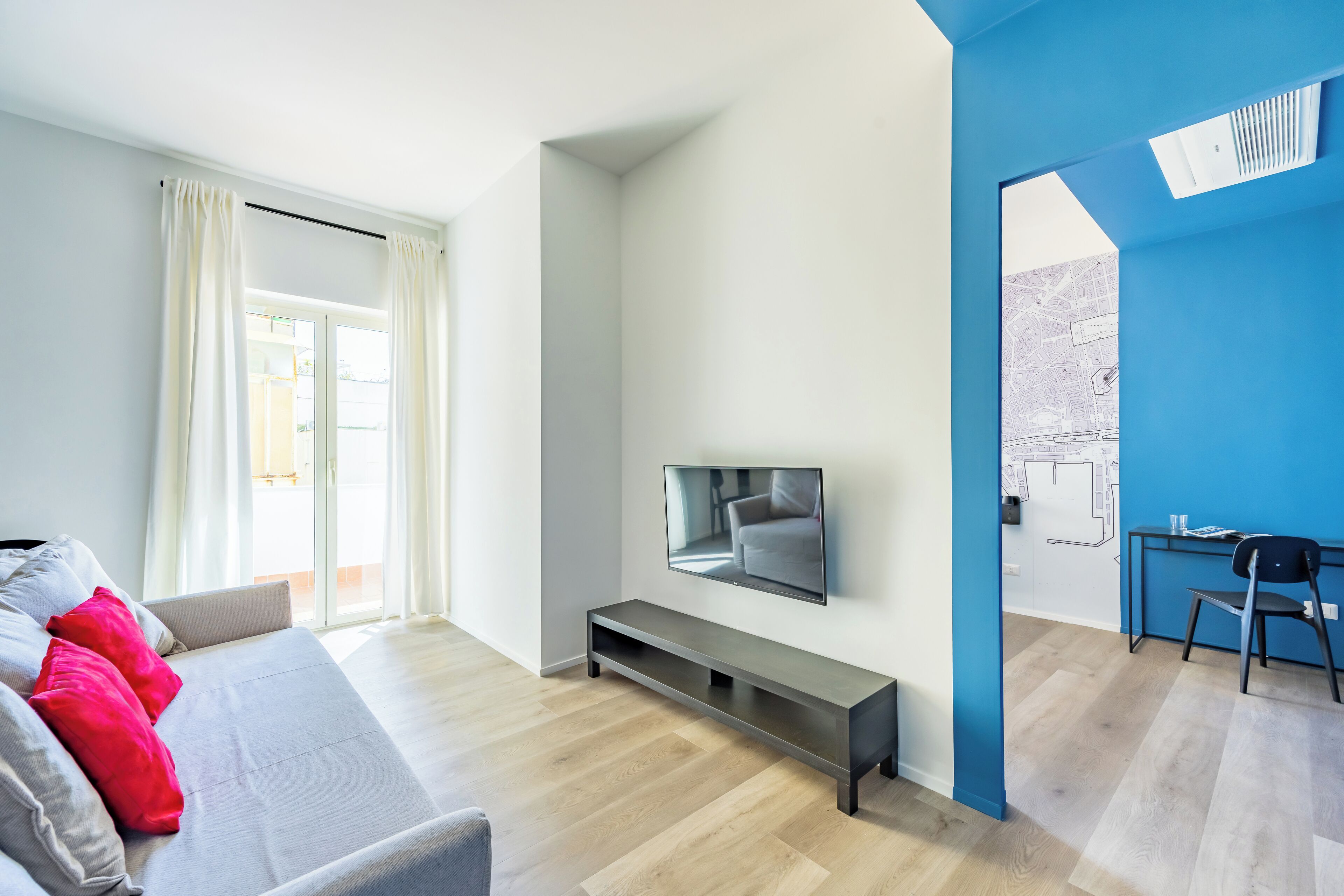 A modern living room with a sofa, TV, and a small desk area.