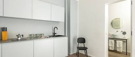 A modern kitchen with white cabinets, a black chair, and a wooden floor.