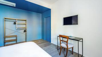 Quarto com cama, escrivaninha com cadeira, televisão e armário com escada.