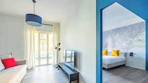 Une chambre d’hôtel moderne équipée d’un canapé, d’une banquette, d’un téléviseur à écran plat et d’une carte affichée au mur.