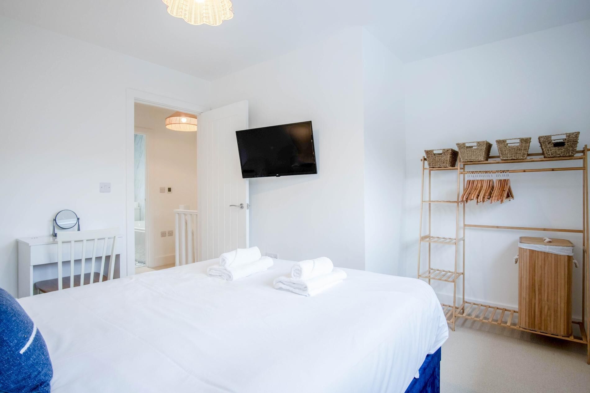 Quarto de hotel com uma cama, televisão na parede, armário de madeira e berço branco.