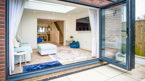 A modern interior with a living area, a staircase, and a kitchen. - Hatherleigh Drive - 2 Bedroom House - Mumbles (Swansea)