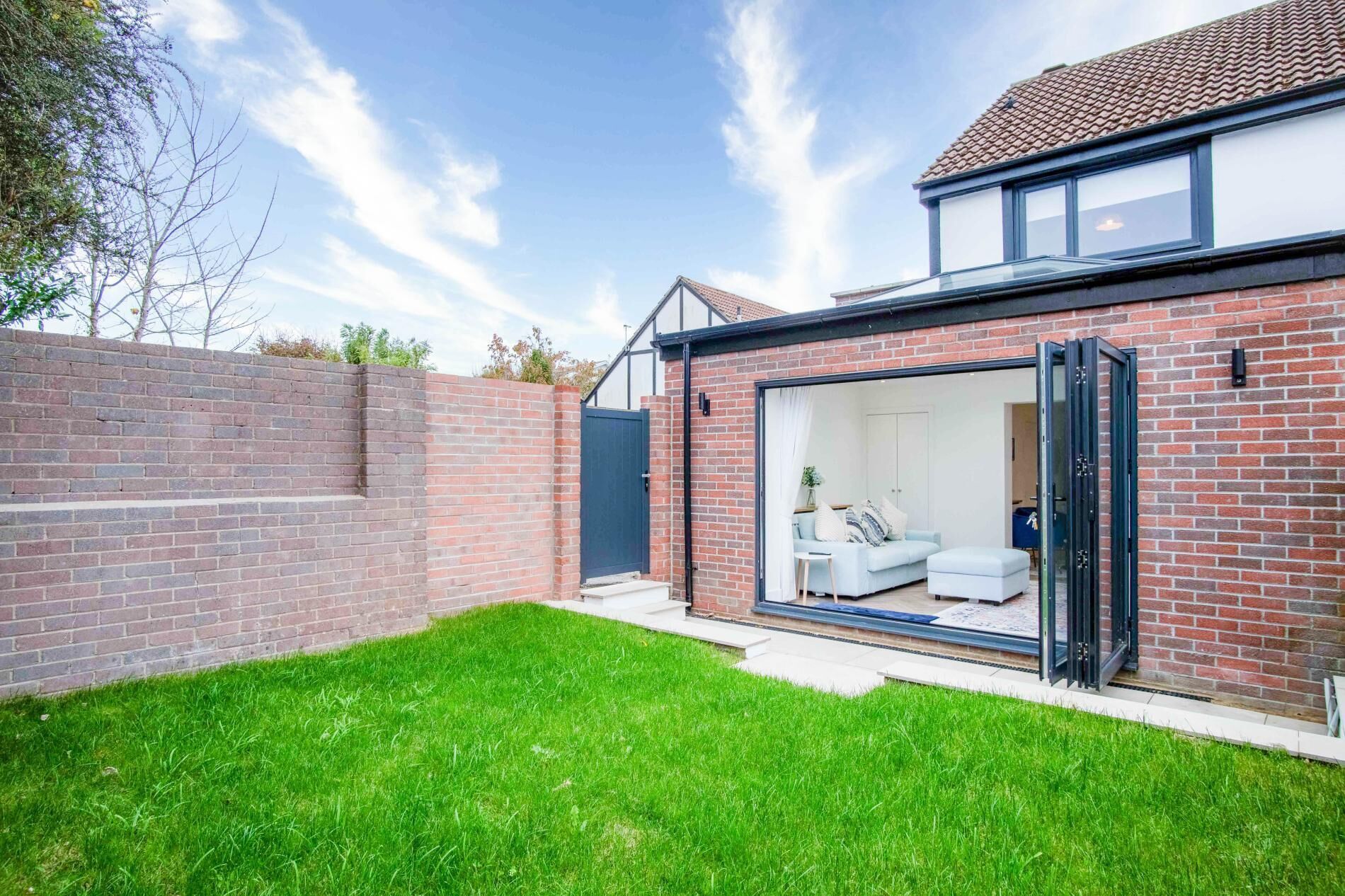 A modern house with a brick exterior, a glass door leading to a living room with a sofa and a coffee table.
