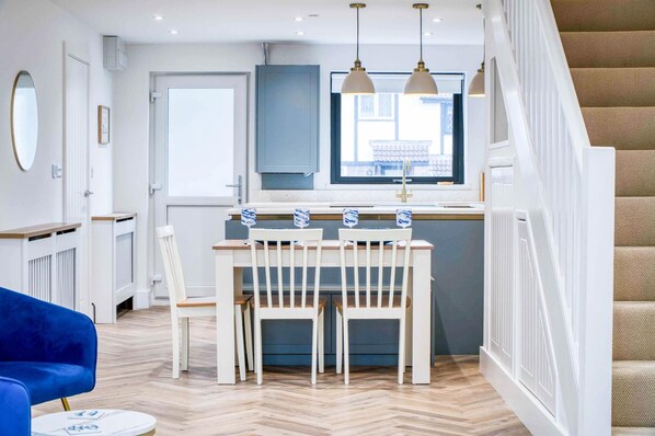 Una cocina moderna con comedor, una silla azul y una escalera.