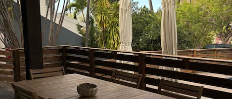 Una terraza de madera con una mesa y sillas, rodeada de palmeras y vistas del paisaje.