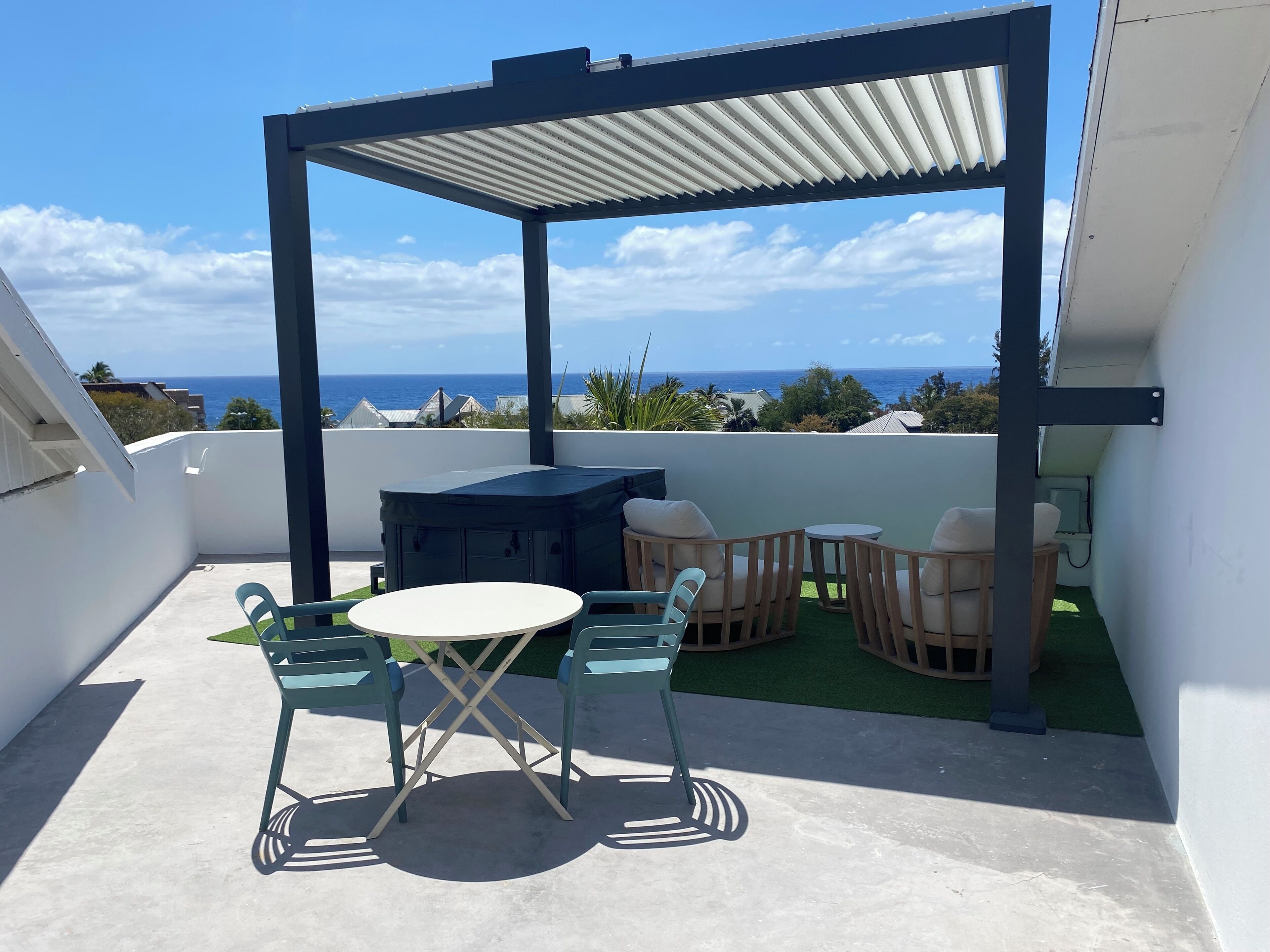 Un espacio de estar al aire libre techado con un jacuzzi, una mesa y sillas.