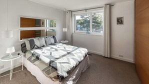 A bedroom with a bed, bedside tables, a window, and a mirror. - 4 bedroom accommodation in Sarisbury Green, Southampton (Sarisbury Green, Southampton)
