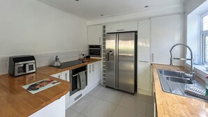 A modern kitchen with a stainless steel refrigerator, a built-in oven, a microwave, a sink with a faucet, and a window providing natural light. - 4 bedroom accommodation in Sarisbury Green, Southampton (Sarisbury Green, Southampton)