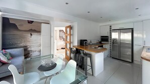 A modern kitchen with a refrigerator, microwave, and a dining area with a glass table and chairs. - 4 bedroom accommodation in Sarisbury Green, Southampton (Sarisbury Green, Southampton)