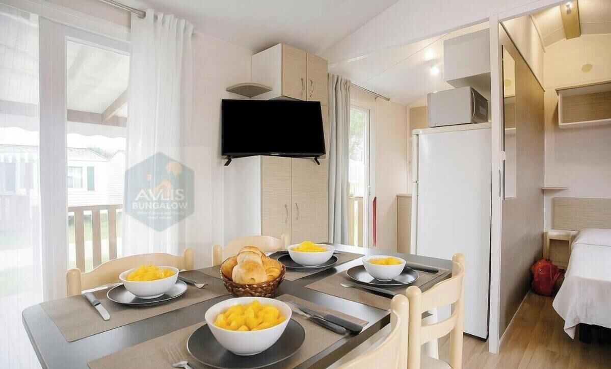 A dining area with a table set for four, bowls of fruit, and a television mounted above the table.