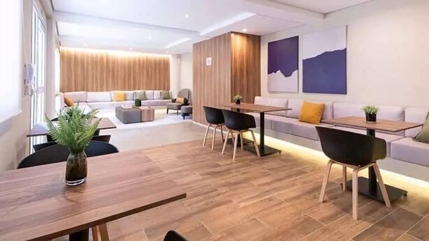 A modern hotel room with a wooden floor, a dining area with a table and chairs, a sofa set, and a large window. - Laguna 430 (São Paulo)