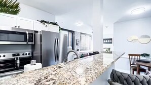 Eine moderne Küche mit Edelstahlgeräten, einer Granitarbeitsplatte und einem Essbereich mit Barhocker.